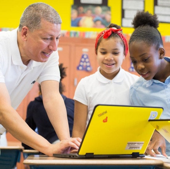 teacher works with middle school students on a computer