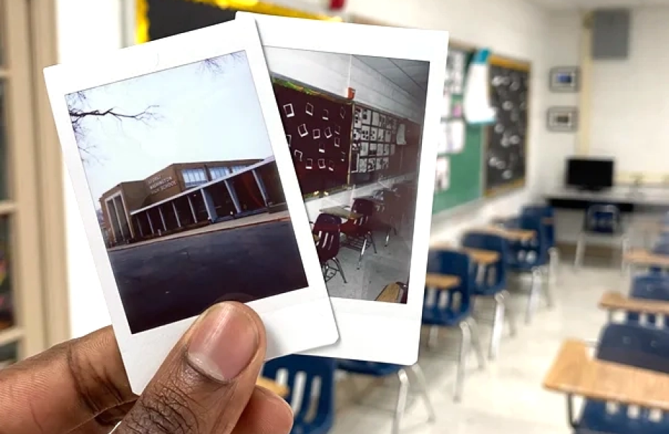 A closeup photograph of a hand holding two poloroids showing photos of a classroom and a school. The photo is taken in a modern classroom